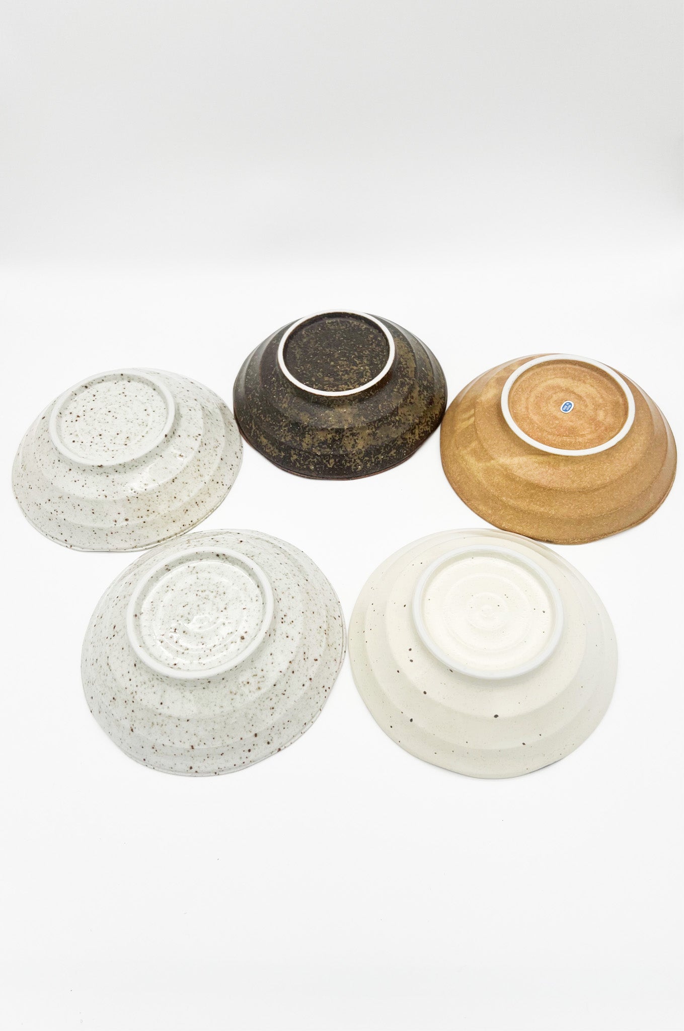 Five ceramic bowls in various colors on a white background