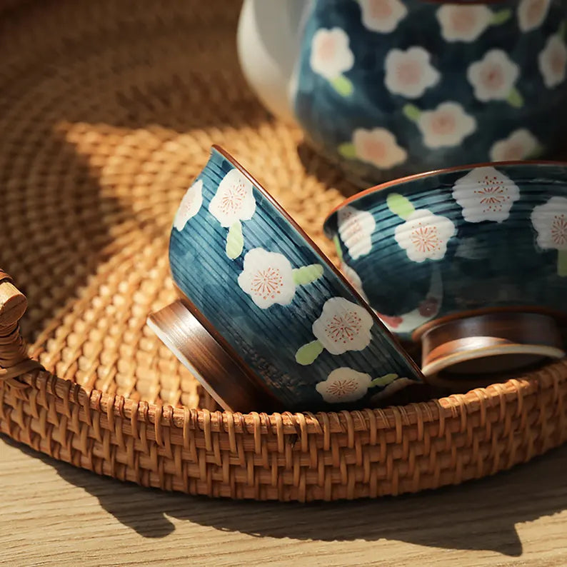 Two ceramic bowls with floral patterns on a woven mat