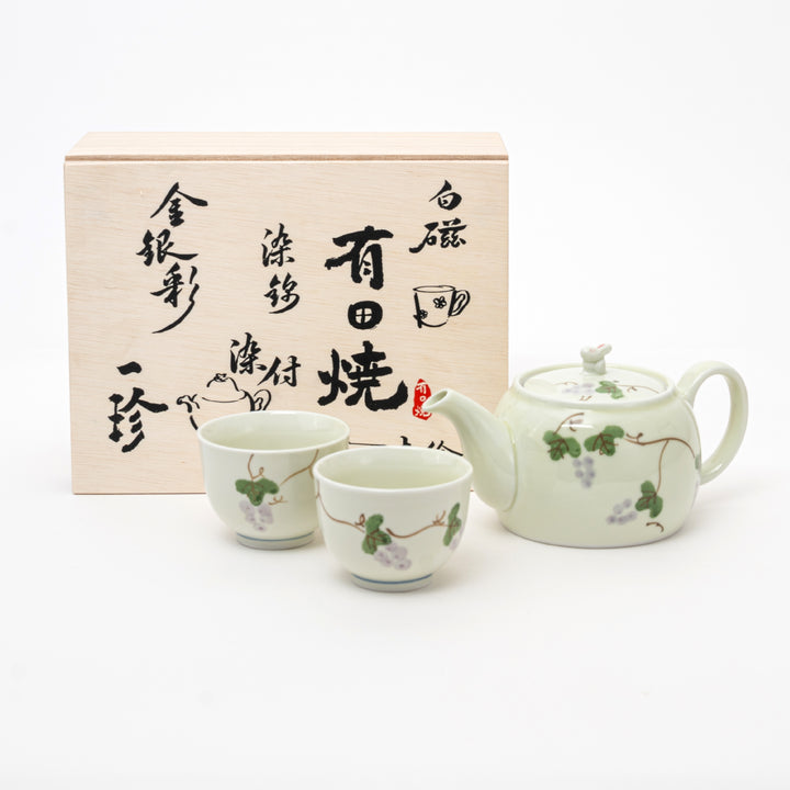 Tea set with teapot and cups in front of a wooden box with Japanese text