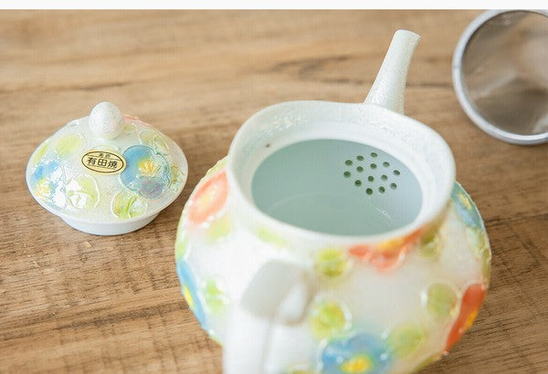 Decorative teapot with floral patterns on a wooden surface