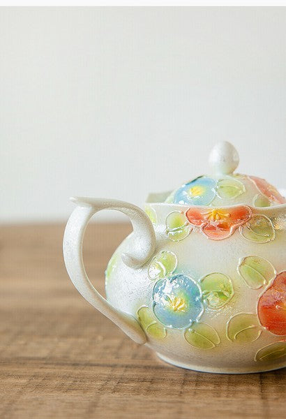 Decorative ceramic teapot with floral patterns on a wooden surface
