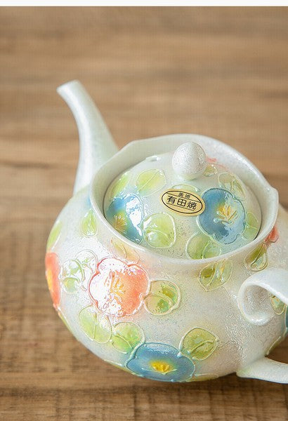 Decorative ceramic teapot with floral patterns on a wooden surface