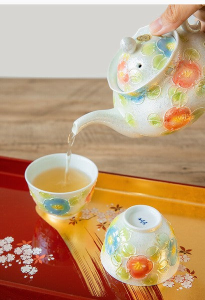 Teapot and cup with floral design on a wooden surface