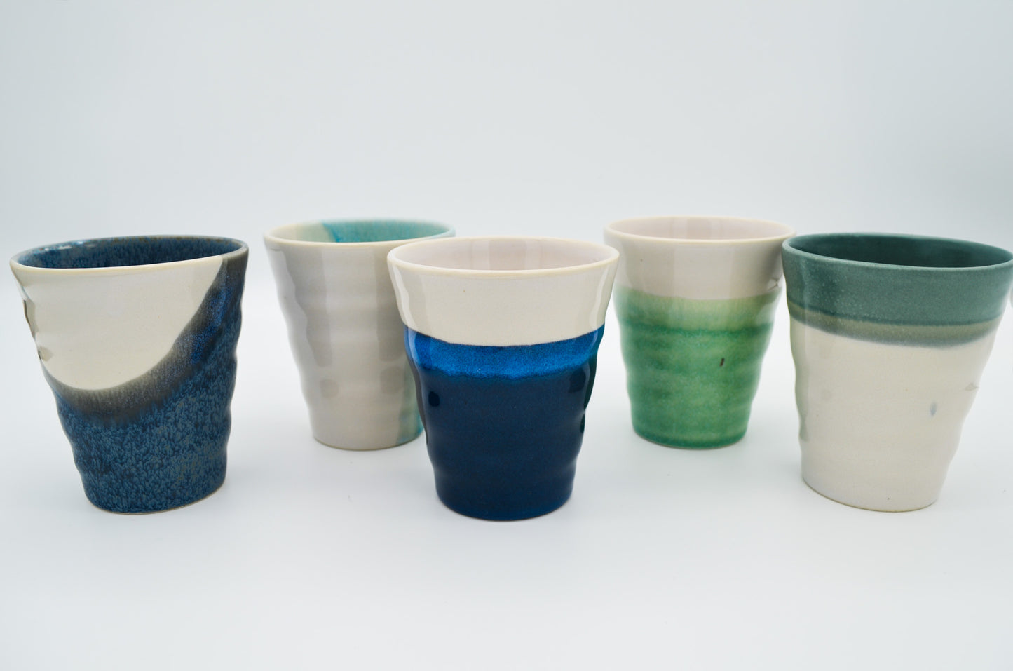Five ceramic cups with gradient colors on a white background