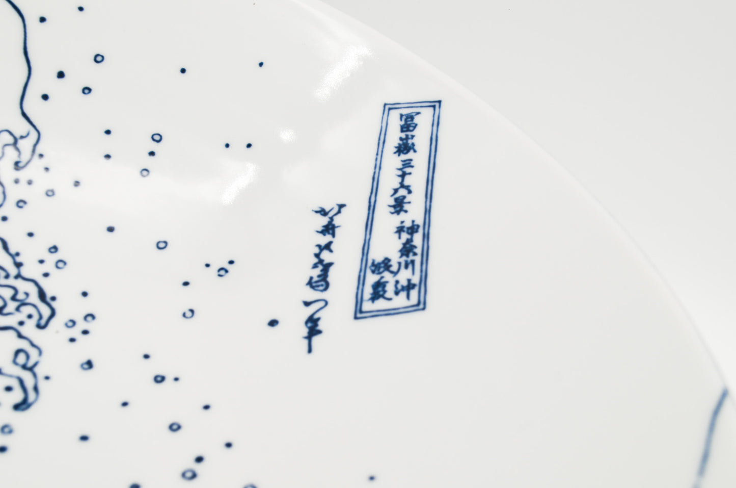 Close-up of a ceramic plate with blue floral patterns and text on a white background