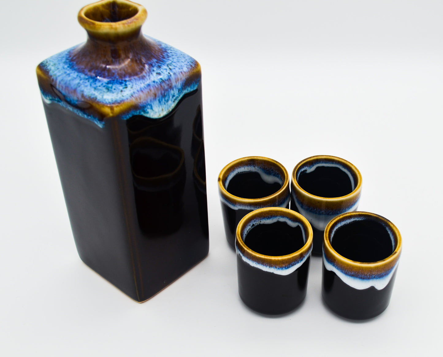 Ceramic bottle with four matching cups on a white background