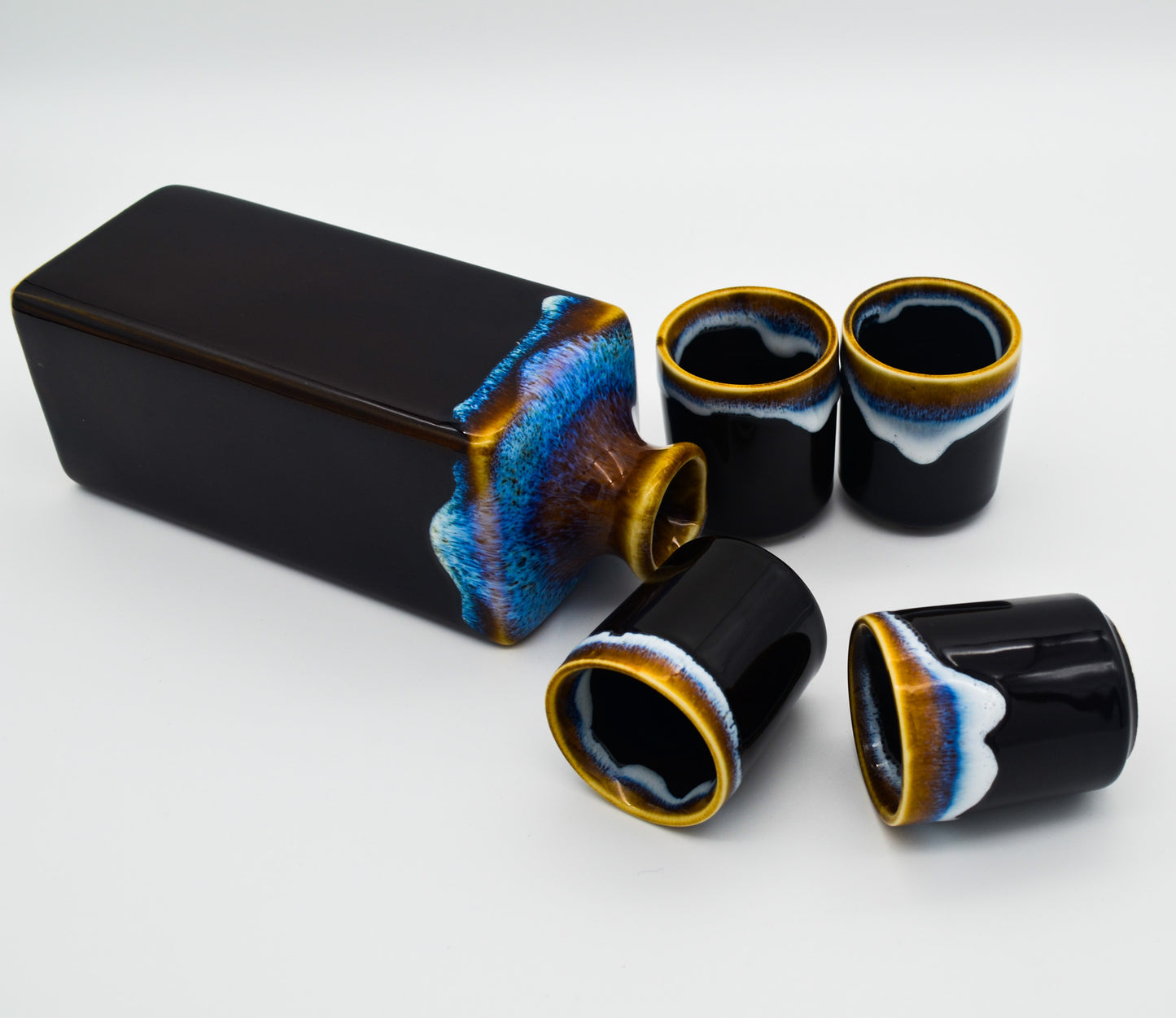 Set of black ceramic cups with colorful interior designs on a white background