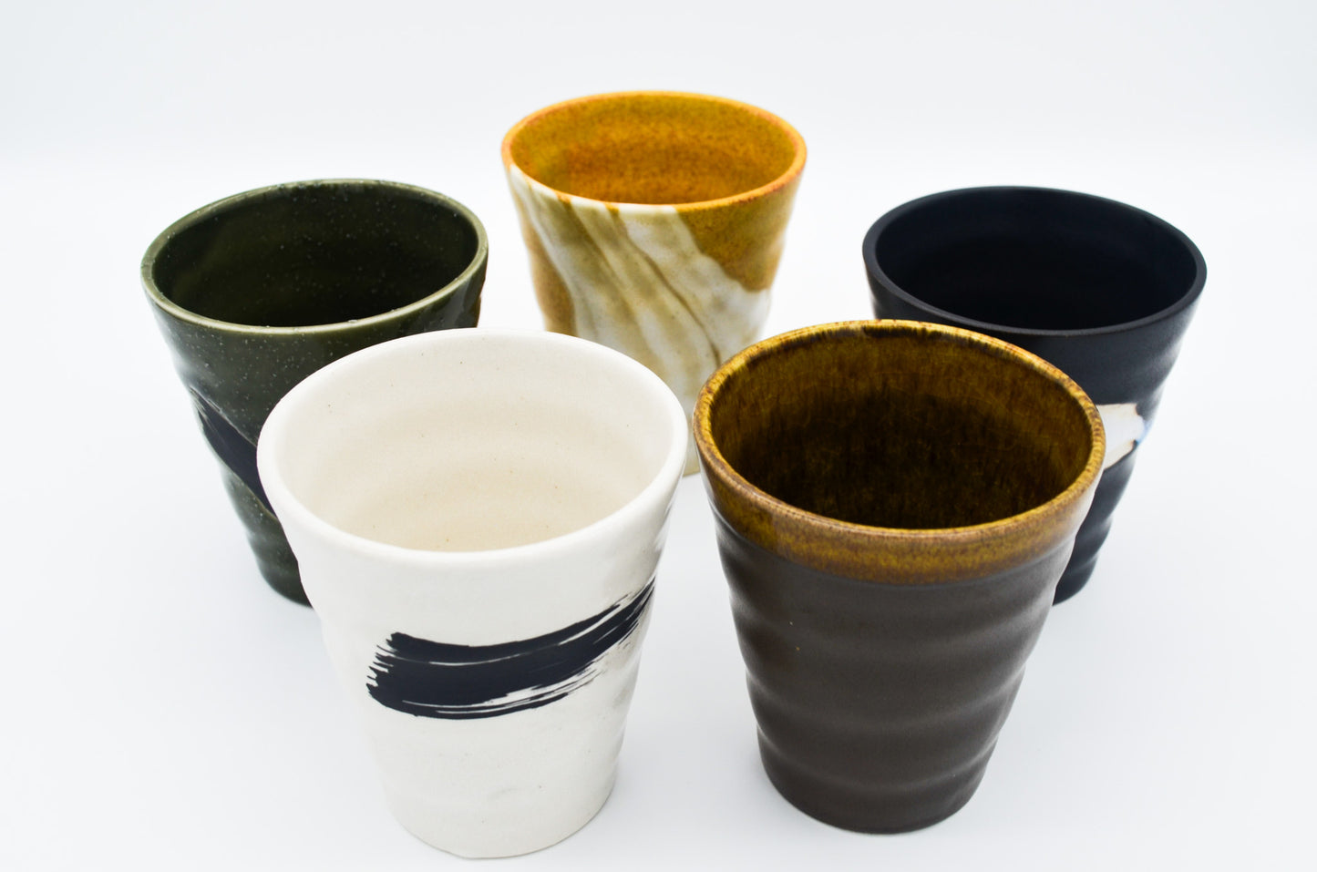 Set of five ceramic cups with different designs on a white background