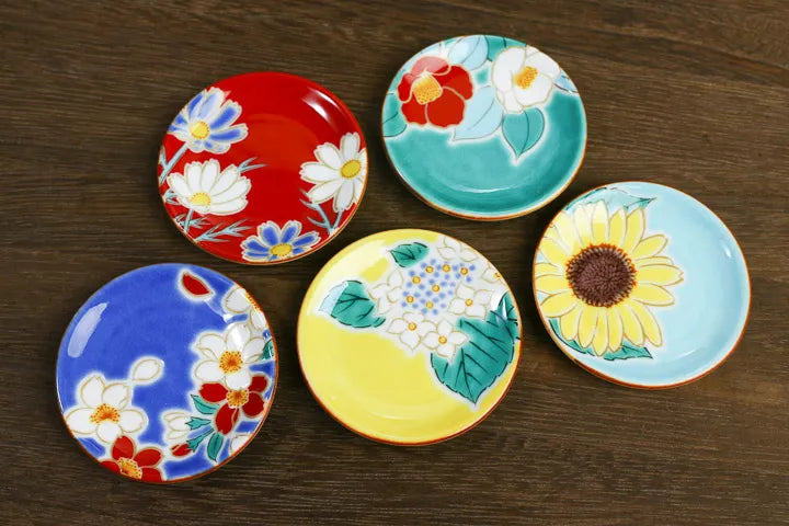 Five colorful ceramic plates with floral designs on a wooden surface