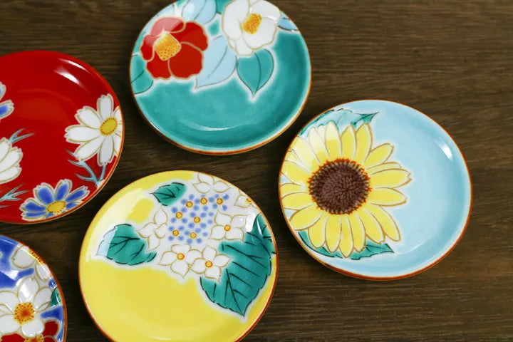 Set of colorful ceramic plates with floral designs on a wooden surface