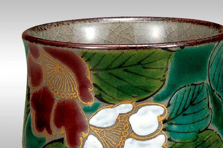 Decorative ceramic cup with floral and leaf patterns on a white background