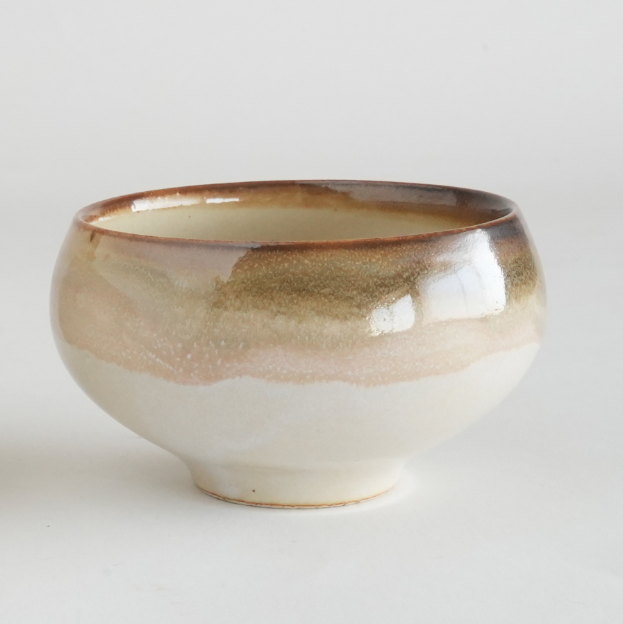 Ceramic bowl with brown and beige glaze on a white background