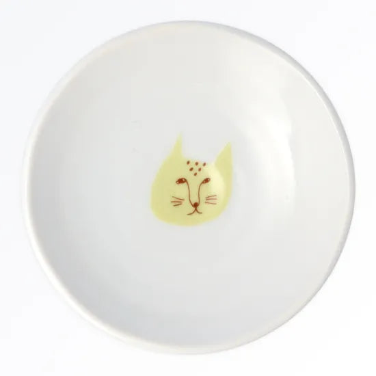 Round white plate with a yellow cat face design on a white background
