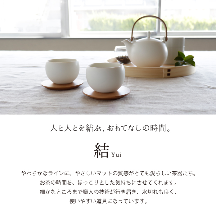 Tea set with teapot and cups on a wooden tray in a bright room.