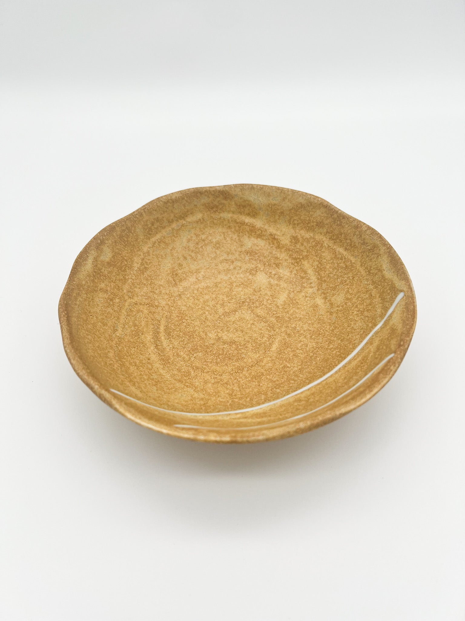 Round ceramic plate with a textured surface on a white background