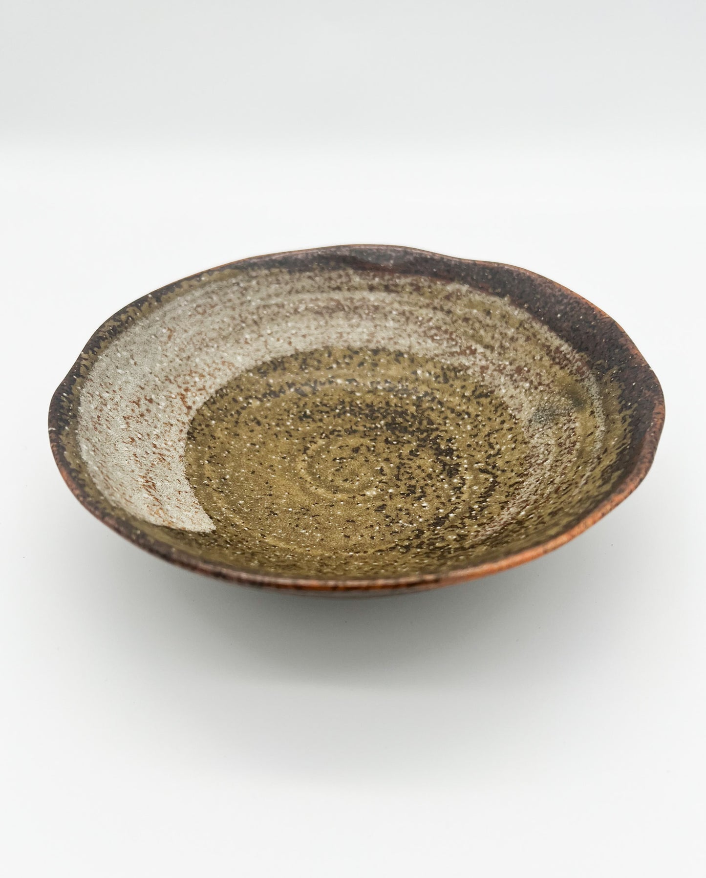 Ceramic plate with a speckled glaze on a white background