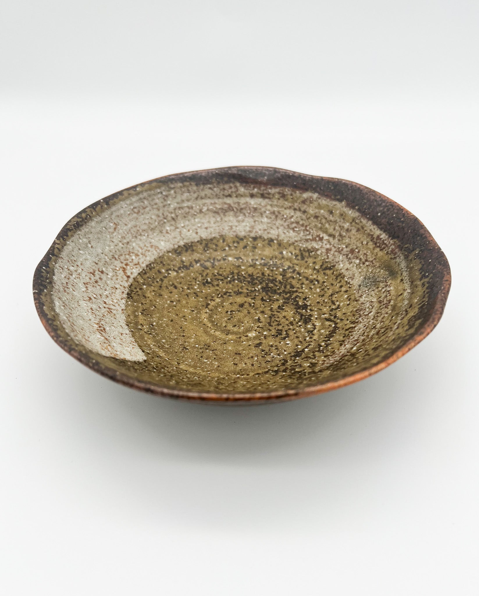 Ceramic plate with a speckled glaze on a white background