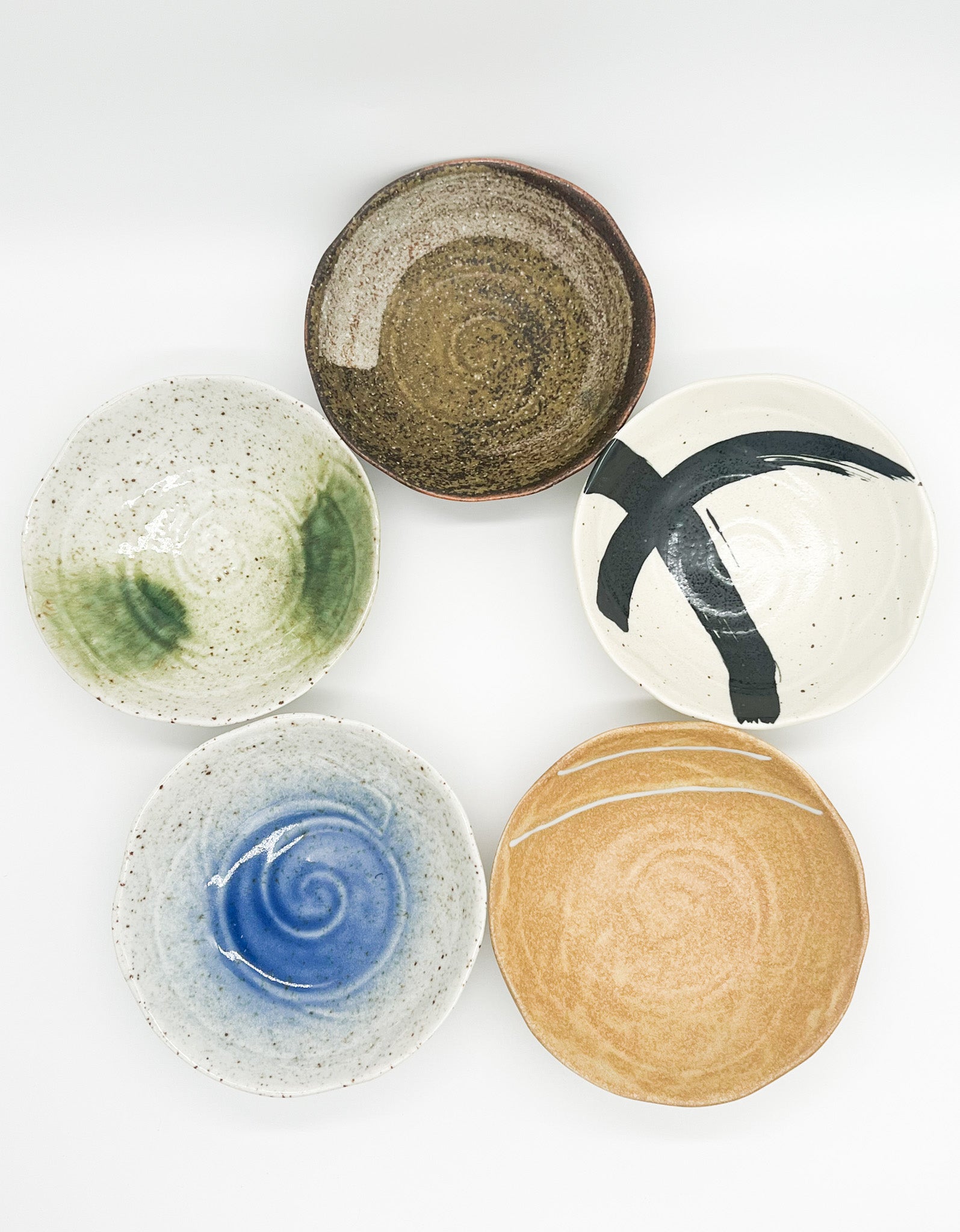 Five ceramic bowls with different designs and colors on a white background