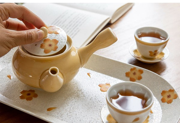 Tea set with a teapot and cups on a tablecloth with floral patterns