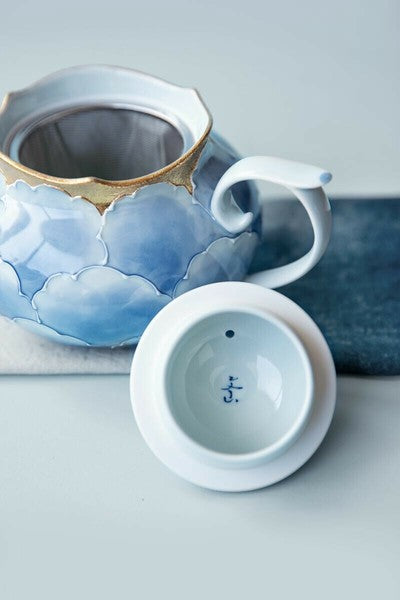 Ceramic teapot with floral design on a light gray background
