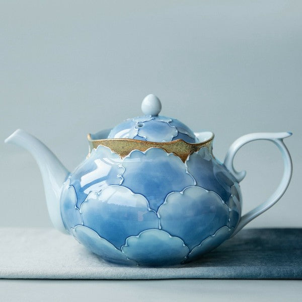 Ceramic teapot with blue cloud design on a gray background