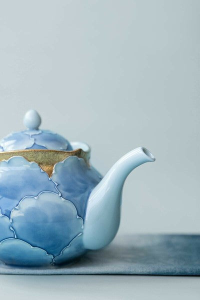 Ceramic teapot with blue floral design on a light gray background