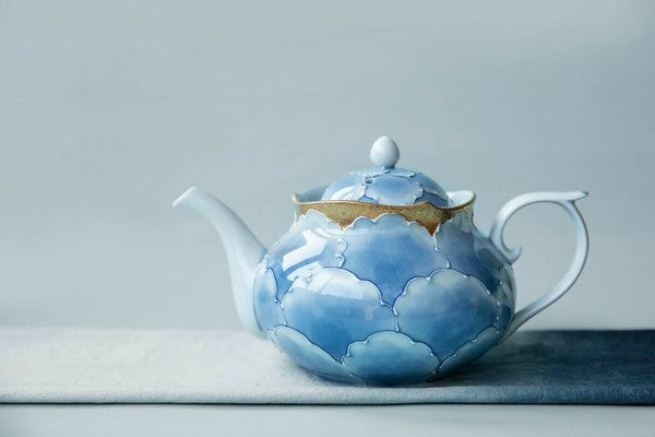 Ceramic teapot with blue cloud design on a gray background