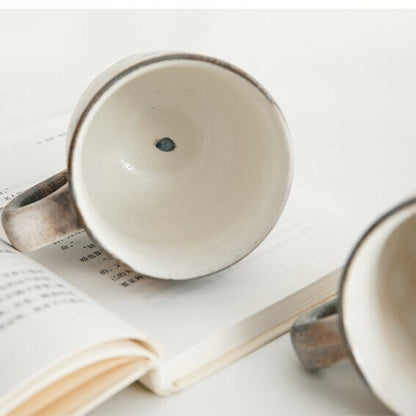 Two ceramic mugs on an open book with a white background. Japanese Ceramics. Made in Japan.