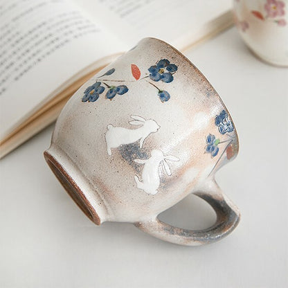 Ceramic mug with floral and rabbit designs on a light surface. Japanese Ceramics. Made in Japan.