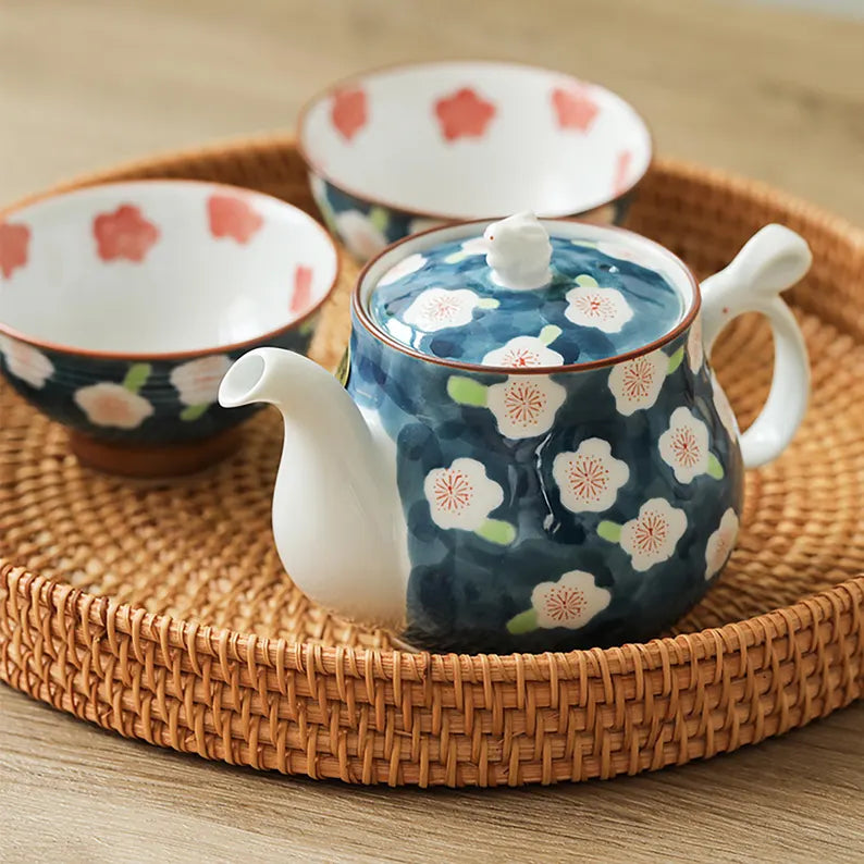 Ceramic teapot and bowl with floral design on a woven tray