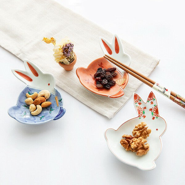 Set of rabbit-shaped ceramic dishes with snacks on a white surface