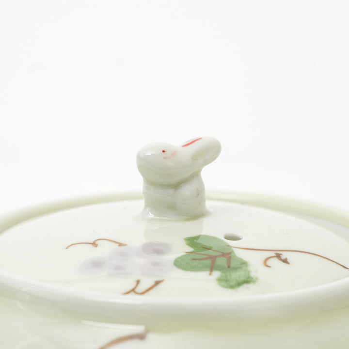 Ceramic teapot lid with a cat-shaped knob on a white background
