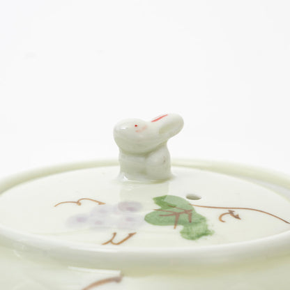 Ceramic teapot lid with a cat-shaped knob on a white background
