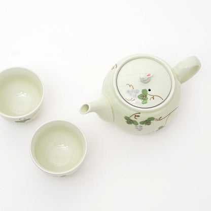 Ceramic teapot and two cups with floral designs on a white background