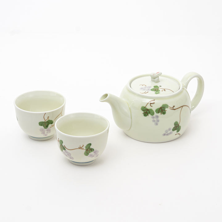 Ceramic teapot and two cups with vine design on a white background