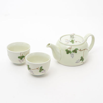 Ceramic teapot and two cups with vine design on a white background