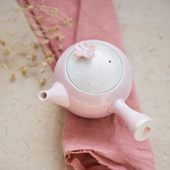 Pink ceramic teapot with a white lid on a pink cloth
