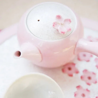 Pink teapot and cup with cherry blossom design on a light pink background