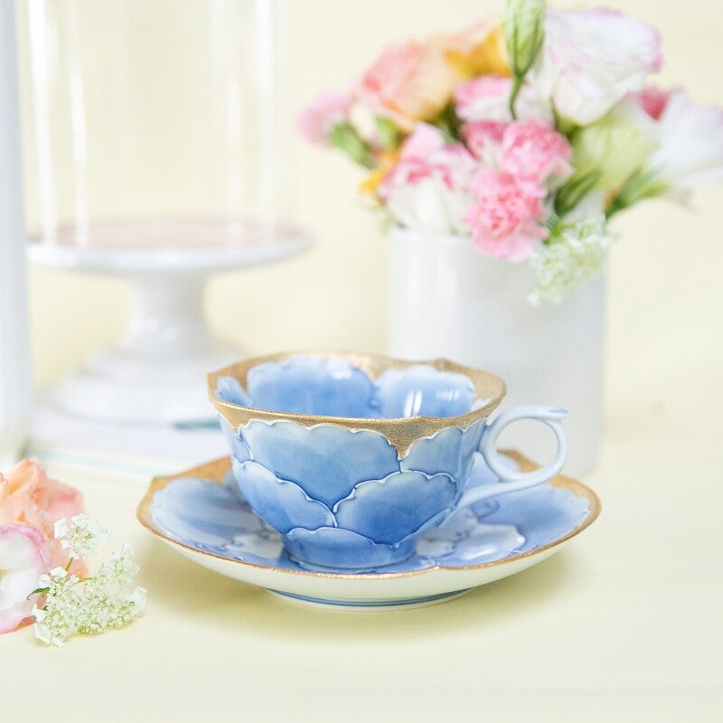 Blue ceramic teacup and saucer with floral design on a light background