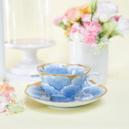 Blue ceramic teacup and saucer with floral design on a light background