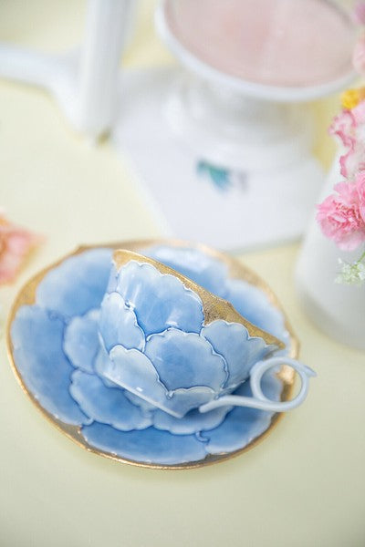Blue ceramic flower on a gold rimmed plate with a blurred background