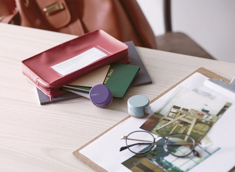 Stack of books, a passport, and a small round object on a table with a blurred background