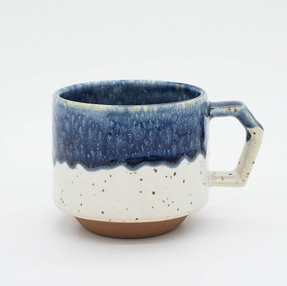 Ceramic mug with blue and white speckled design on a light gray background