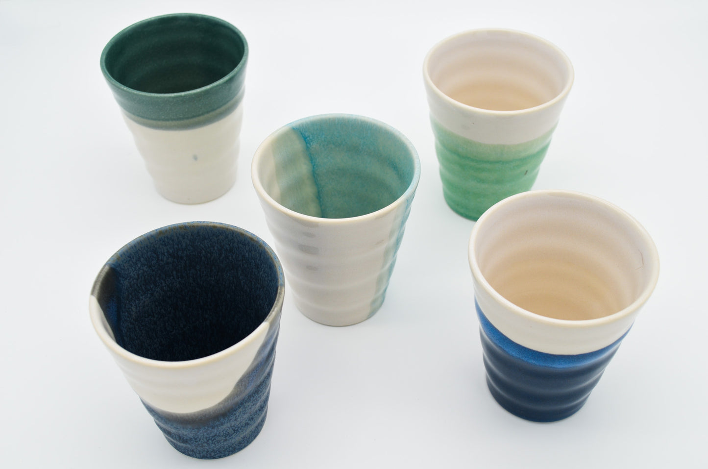 Set of five ceramic cups with gradient colors on a white background