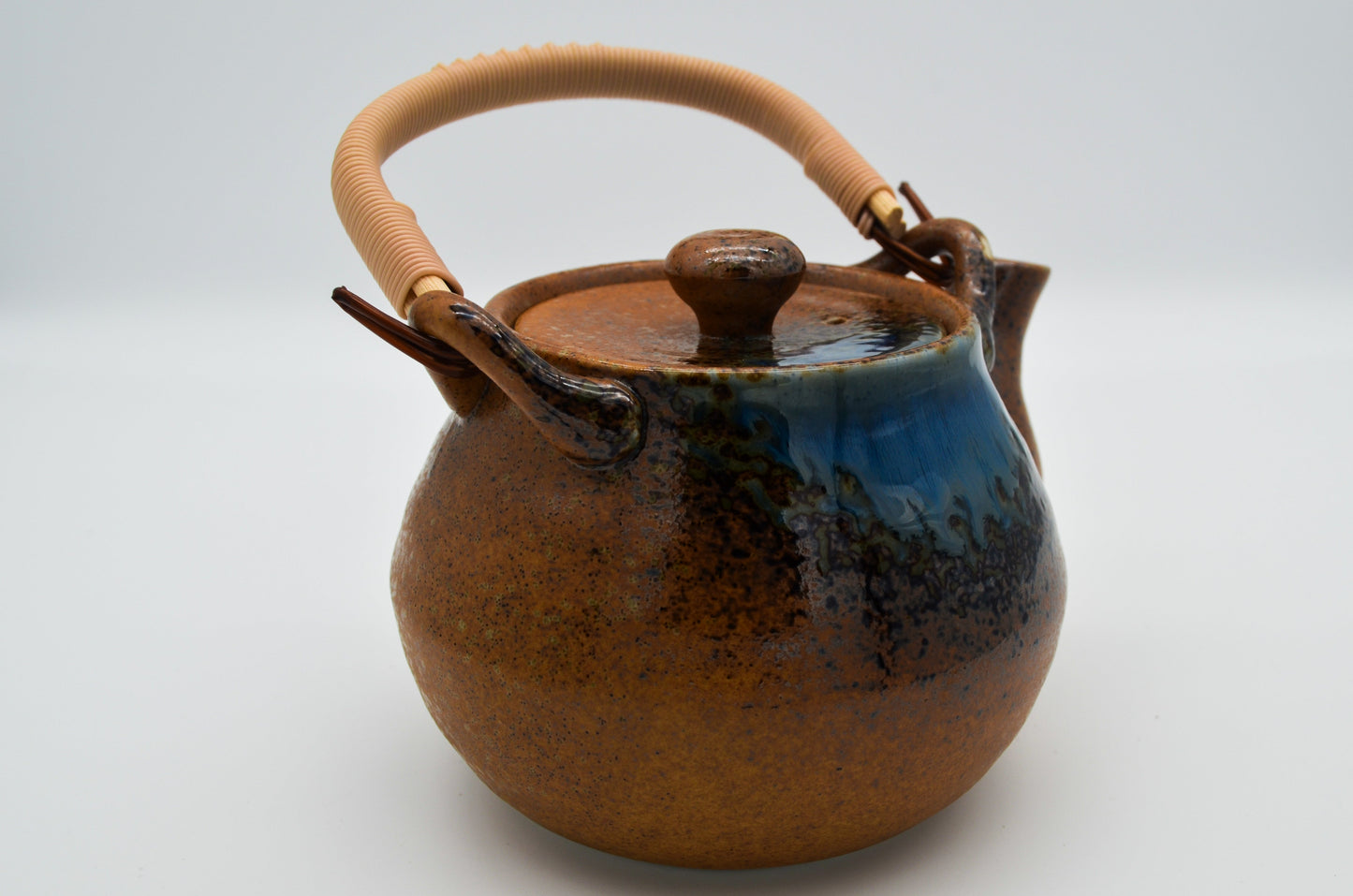 Ceramic teapot with a wooden handle on a light gray background
