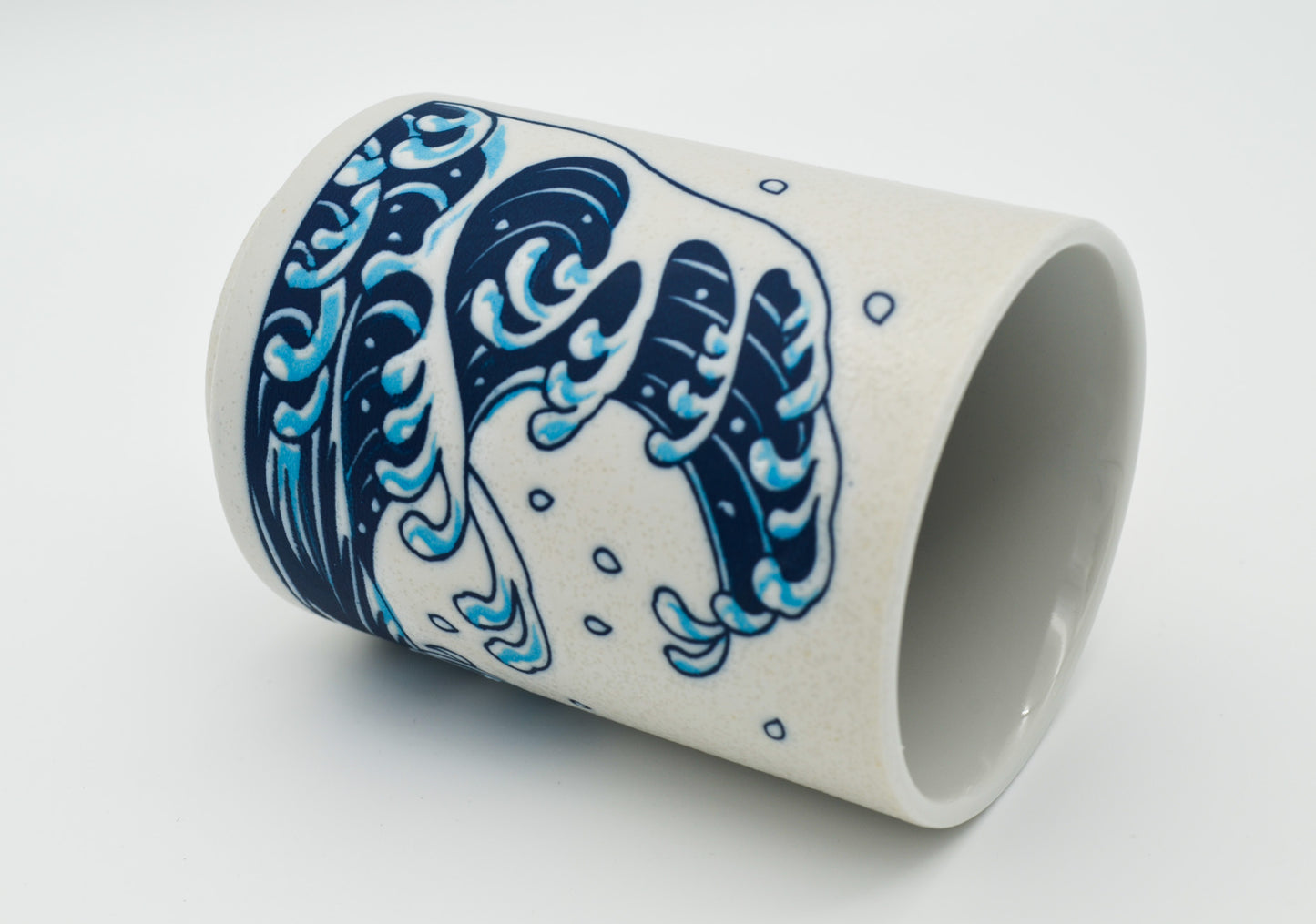 Ceramic cup with blue wave design on a white background