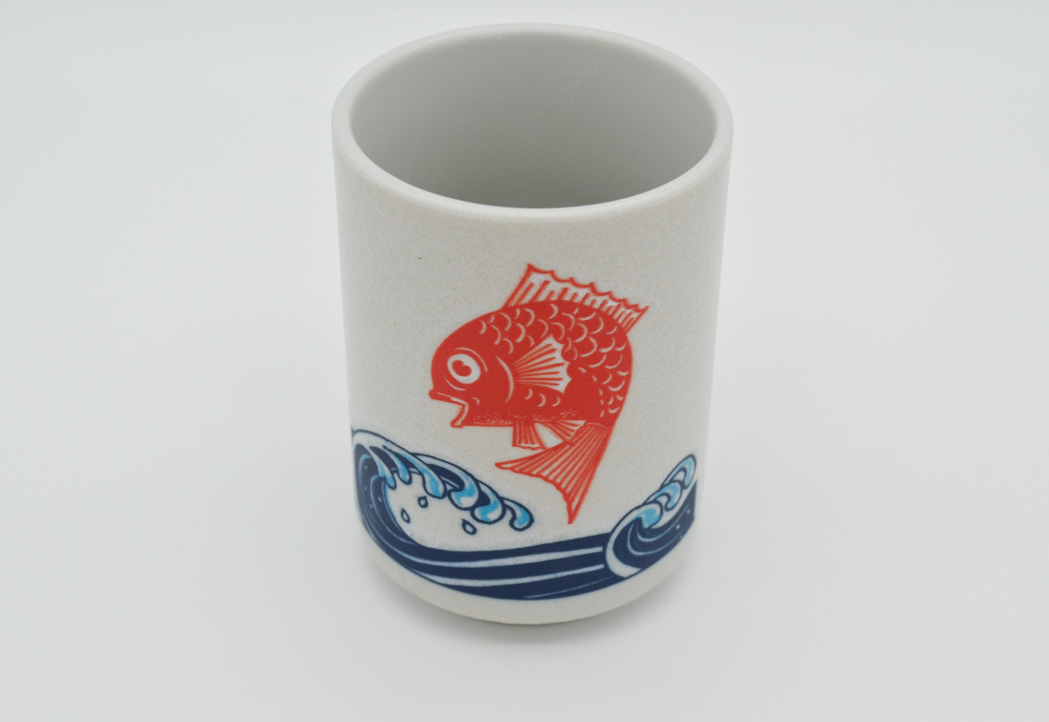 Ceramic cup with a red fish design on a white background