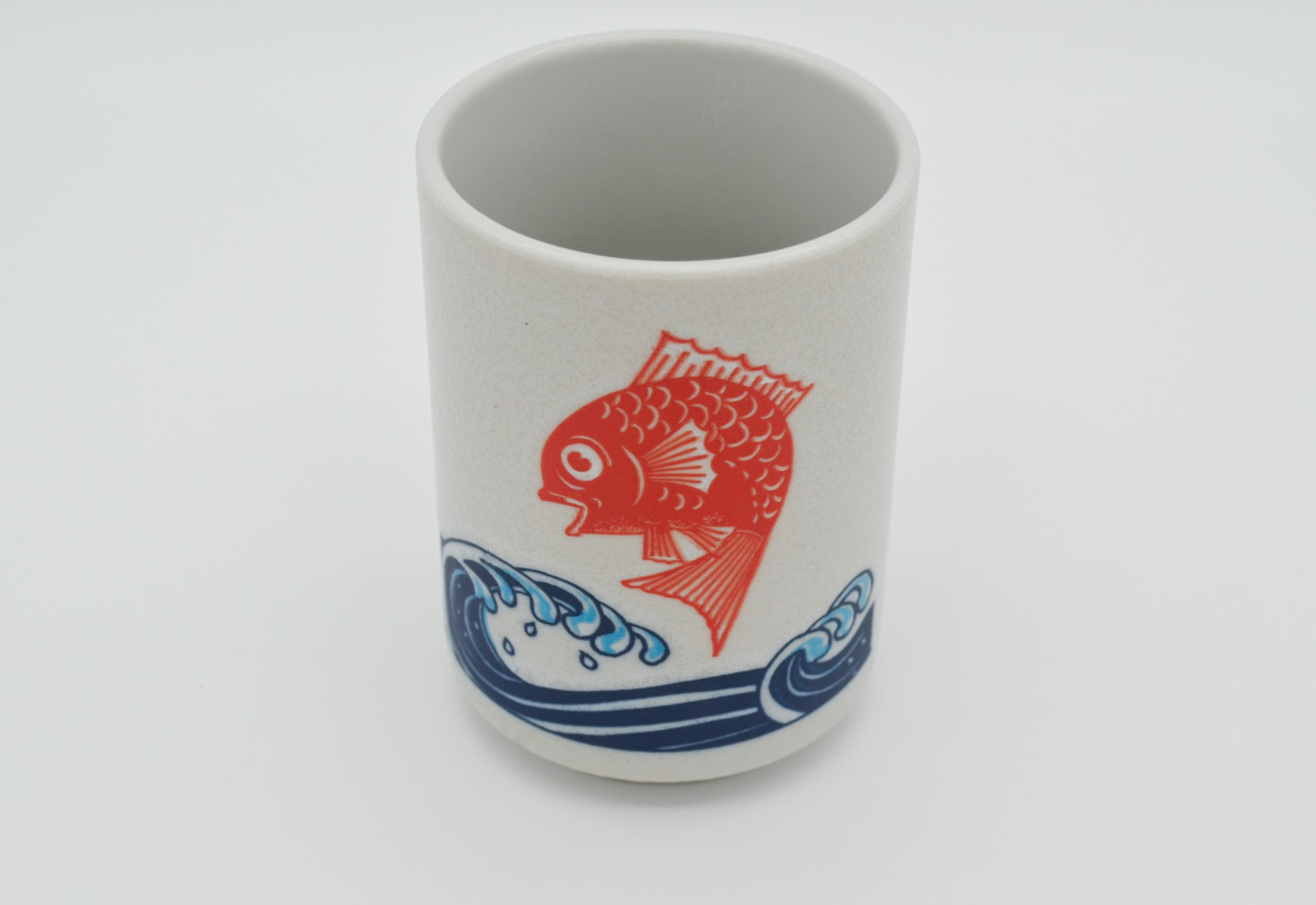 Ceramic cup with a red fish design on a white background