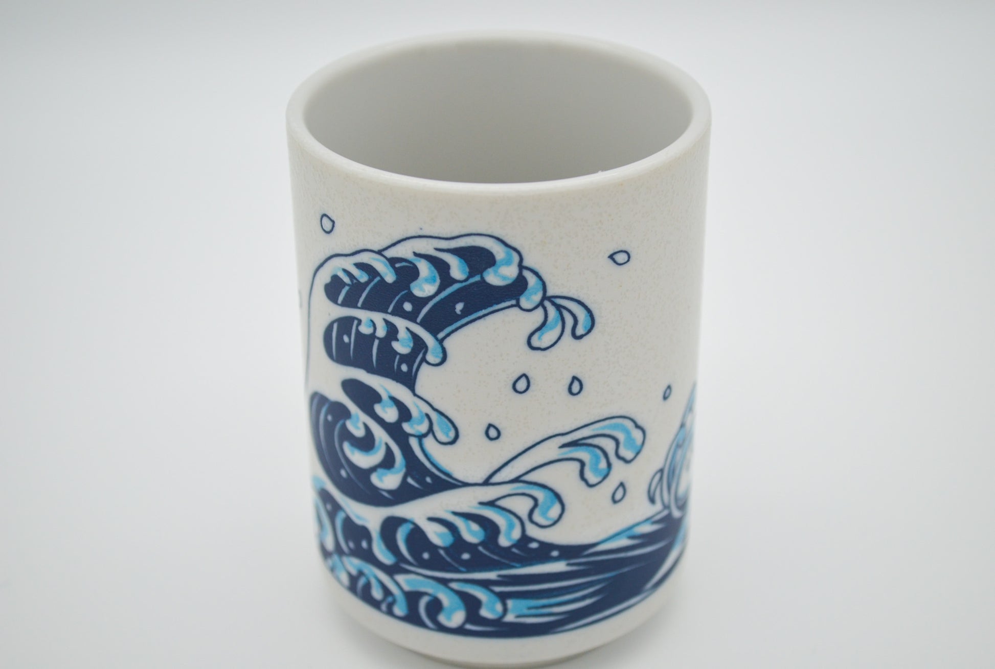 Ceramic cup with blue wave design on a white background