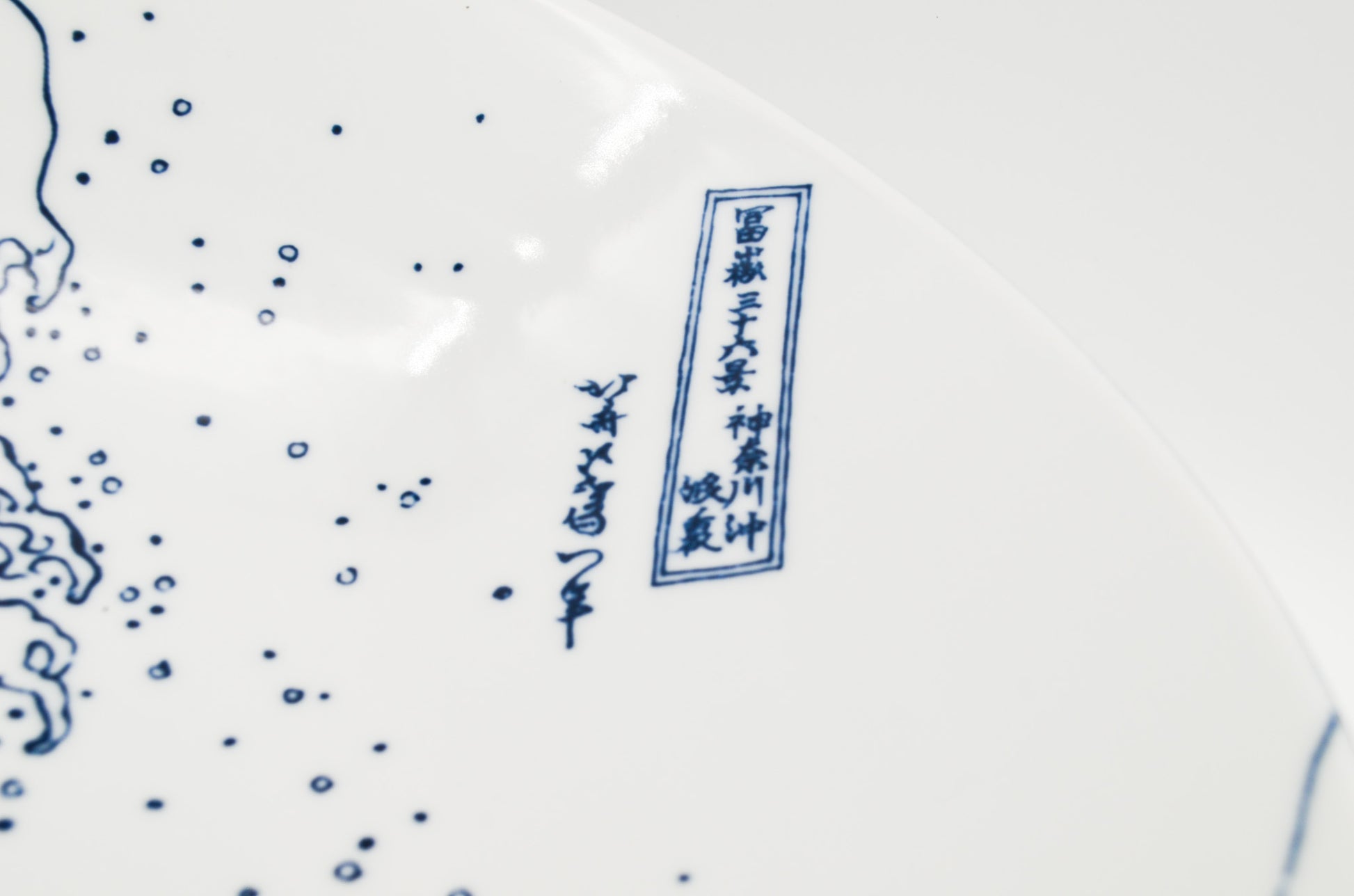 Close-up of a ceramic plate with blue floral patterns and text on a white background
